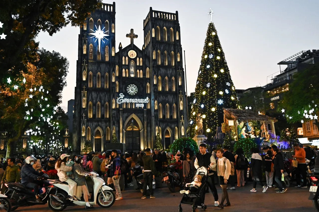 People walk in front of a Christmas tree displayed in front of St. Joseph’s Cathedral in Hanoi, Vietnam, on Dec. 21, 2023. (NHAC NGUYEN/AFP via Getty Images)