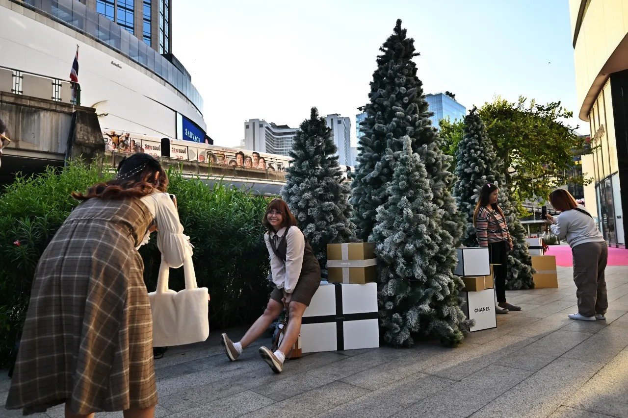 People take pictures with a Chanel Christmas tree display in front of Emquartier shopping mall in Bangkok, Thailand, on Dec. 22, 2023. (LILLIAN SUWANRUMPHA/AFP via Getty Images)