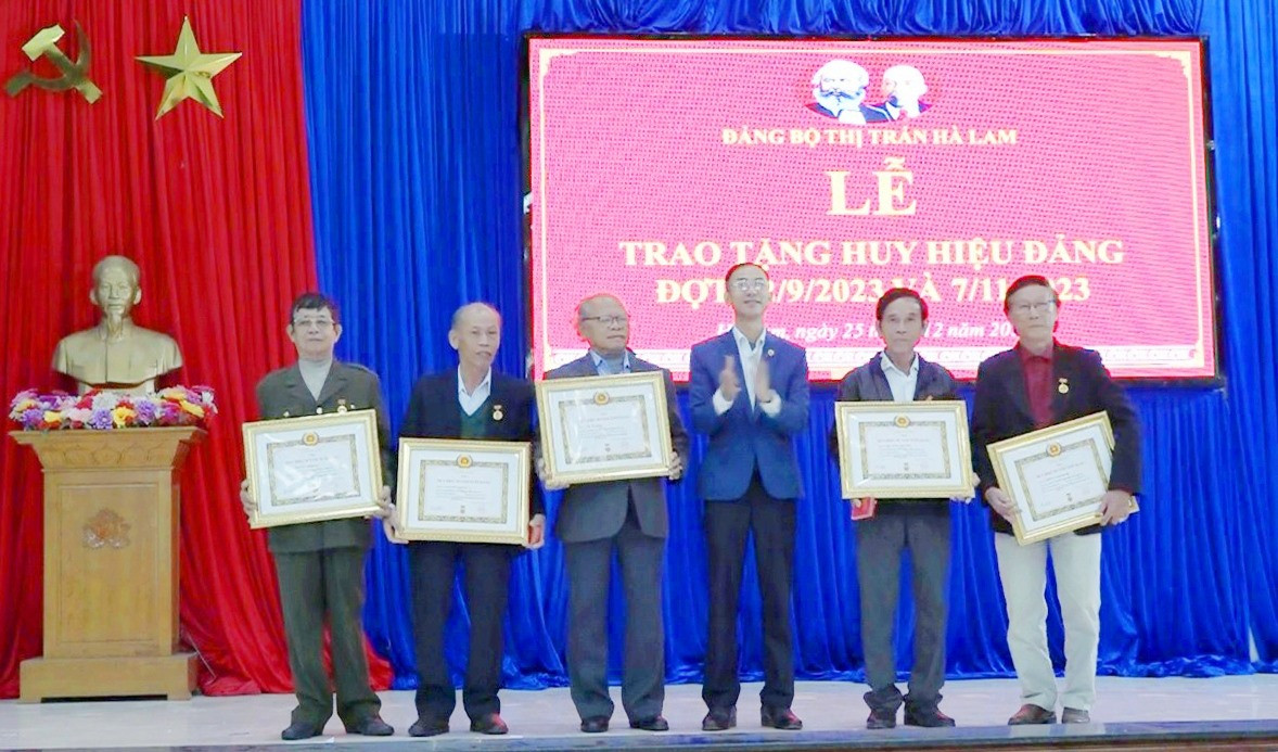 Ông Nguyễn Đình Tư - Bí thư Đảng bộ thị trấn Hà Lam trao huy hiệu đảng cho đảng viên. Ảnh: T.N