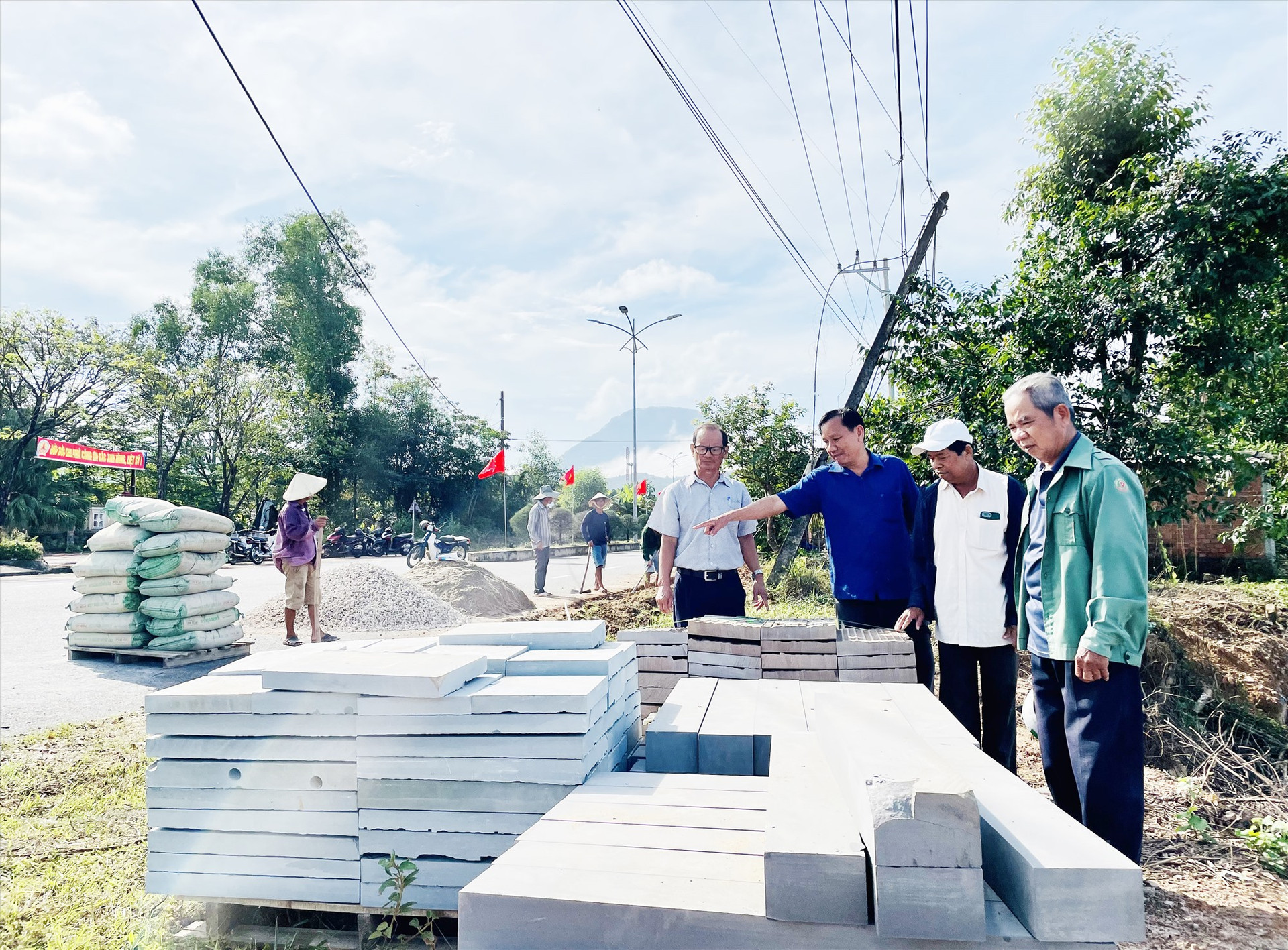 Ông Huỳnh Văn Nguyện (giữa) hướng dẫn việc lát đá lề đường ở thôn Mỹ Sơn (xã Duy Phú). Ảnh: PHI MINH