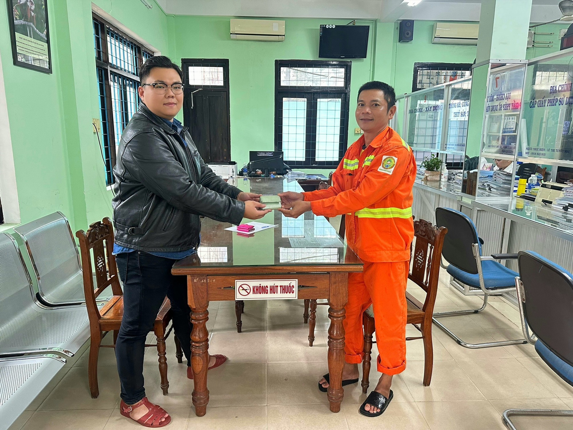 Anh Nguyễn Văn Trung (bên phải) bàn giao tài sản nhặt được cho đại diện Trung tâm hỗ trợ du khách Đà Nẵng.
