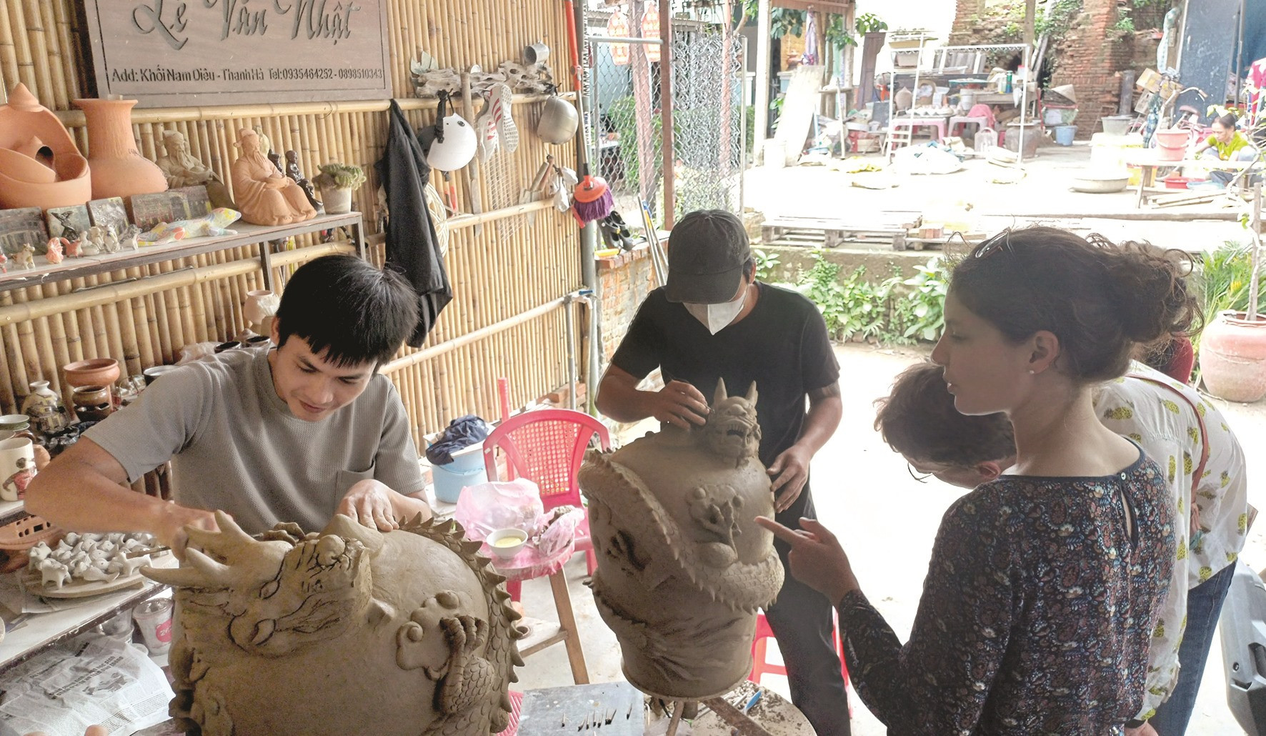 Du khách nước ngoài tò mò và thích thú khi xem thợ làm gốm ở phường Thanh Hà nặn linh vật.