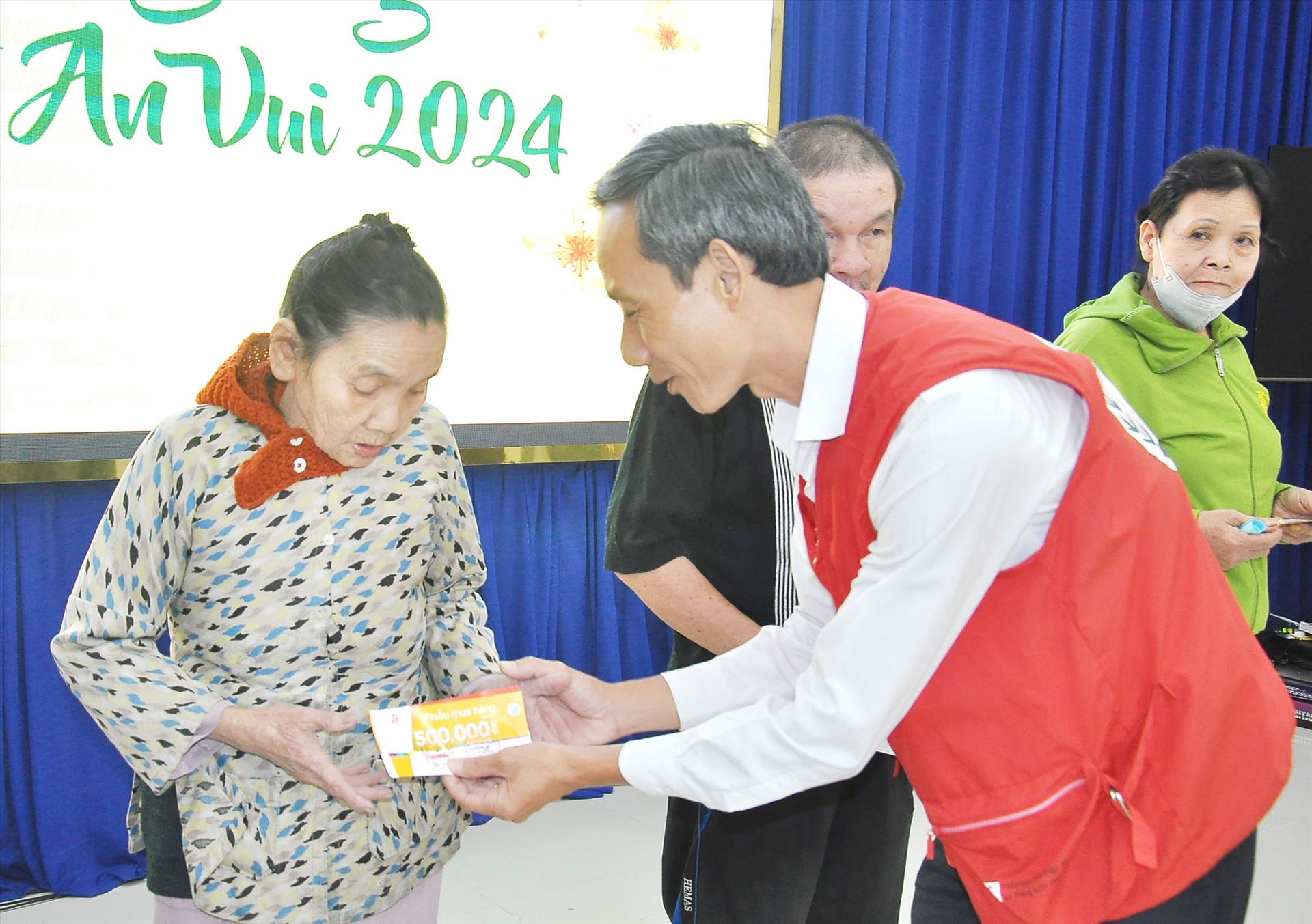 Ông Lê Tấn Minh - Chủ tịch Hội CTĐ tỉnh tặng phiếu mua hàng tại chợ “Tết nhân ái” cho người dân Tam Kỳ. Ảnh: TÂM ĐAN