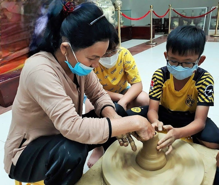 Trẻ em học làm gốm cùng nghệ nhân. Ảnh: CHÂU NỮ