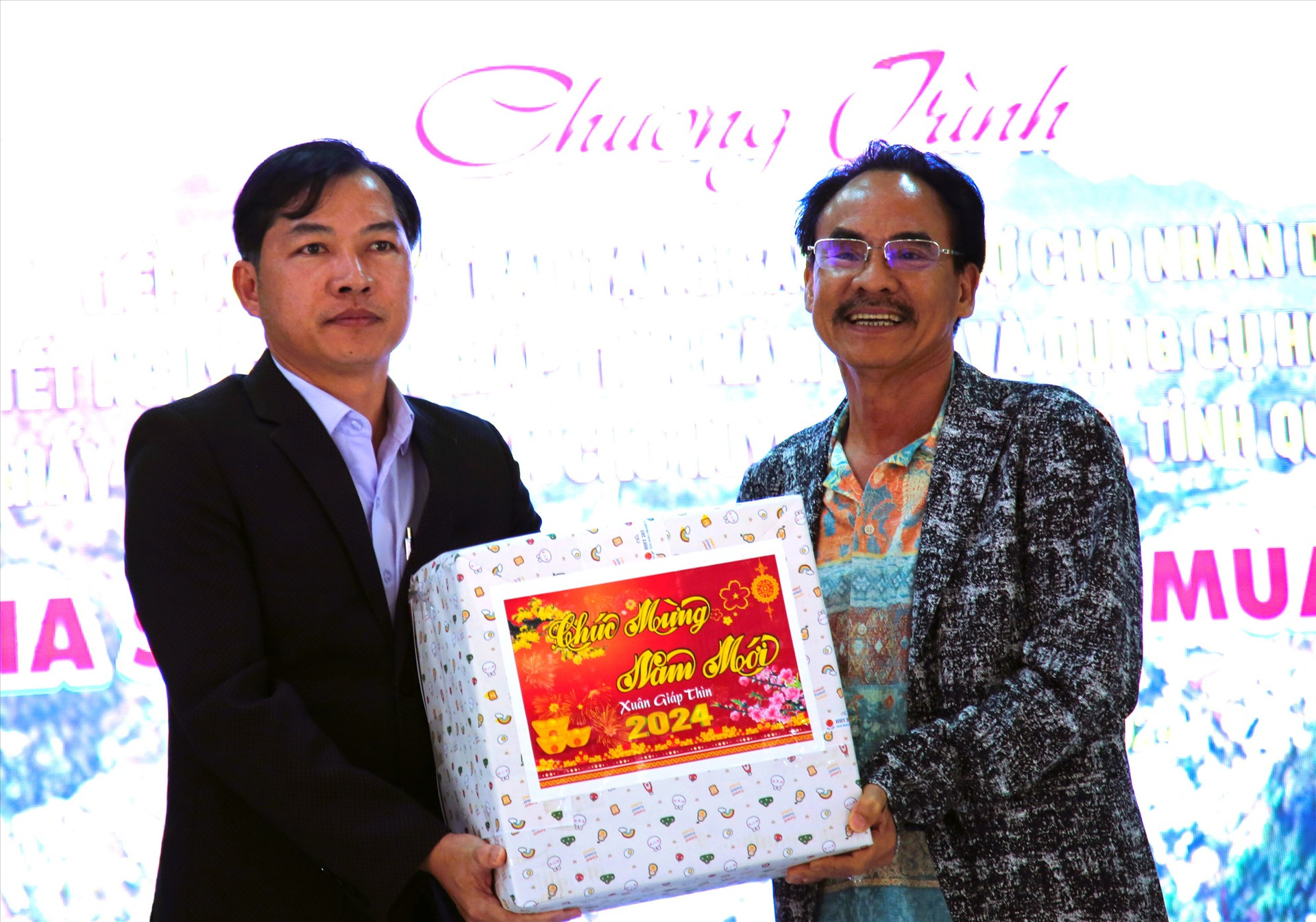 Ông Huỳnh Trung Quang (bên phải) nhận món quà từ lãnh đạo huyện Tây Giang. Ảnh: A.N