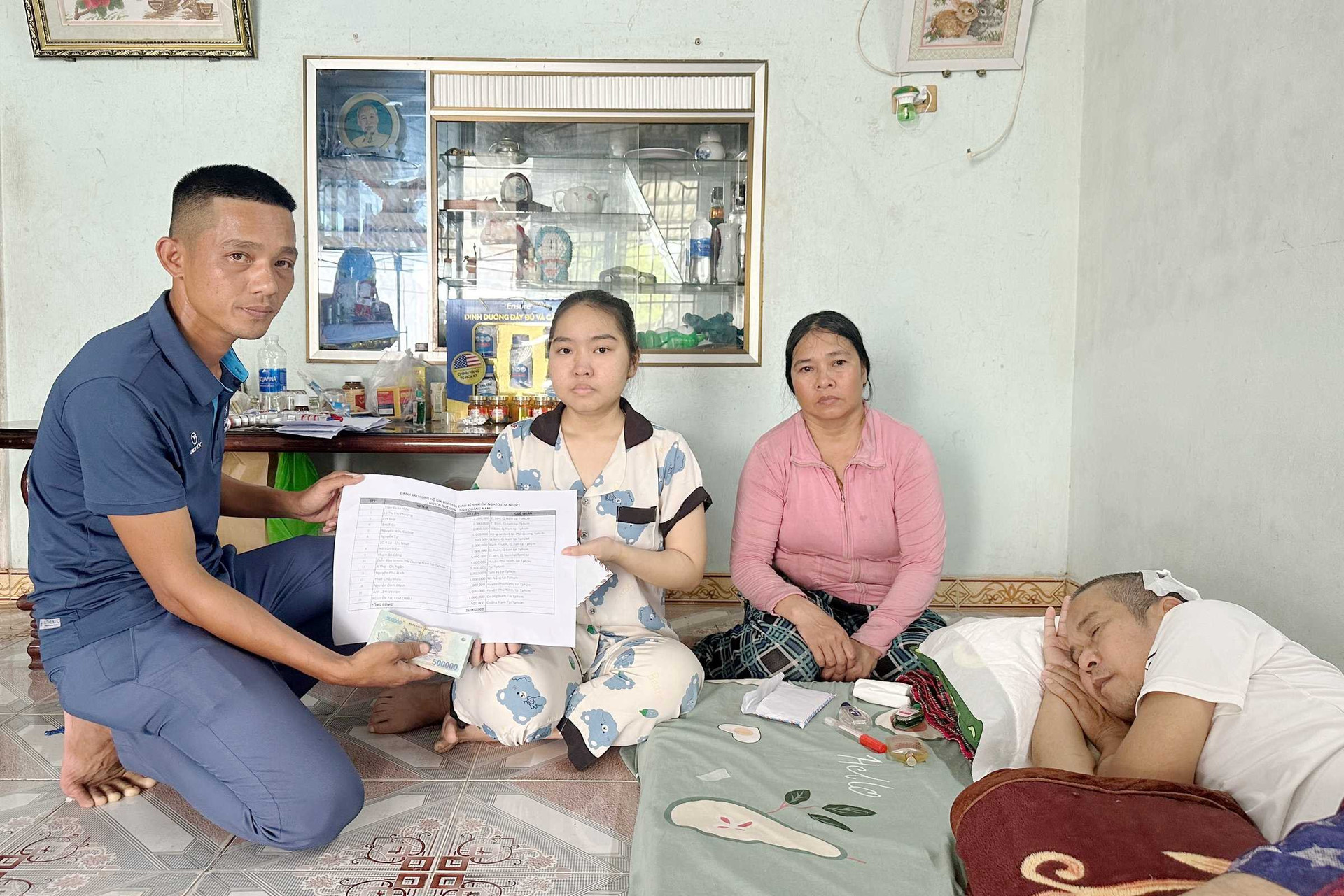 Anh Trần Xuân Vạn thay mặt nhà hảo tâm trao tiền giúp đỡ gia đình chị Lê Trần Như Ngọc. Ảnh: PHAN VINH