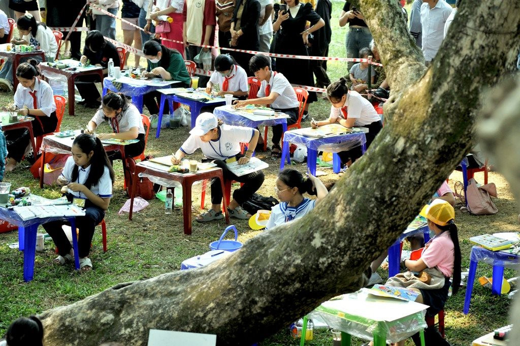 Students compete in a painting contest under the shade of ancient sua trees.