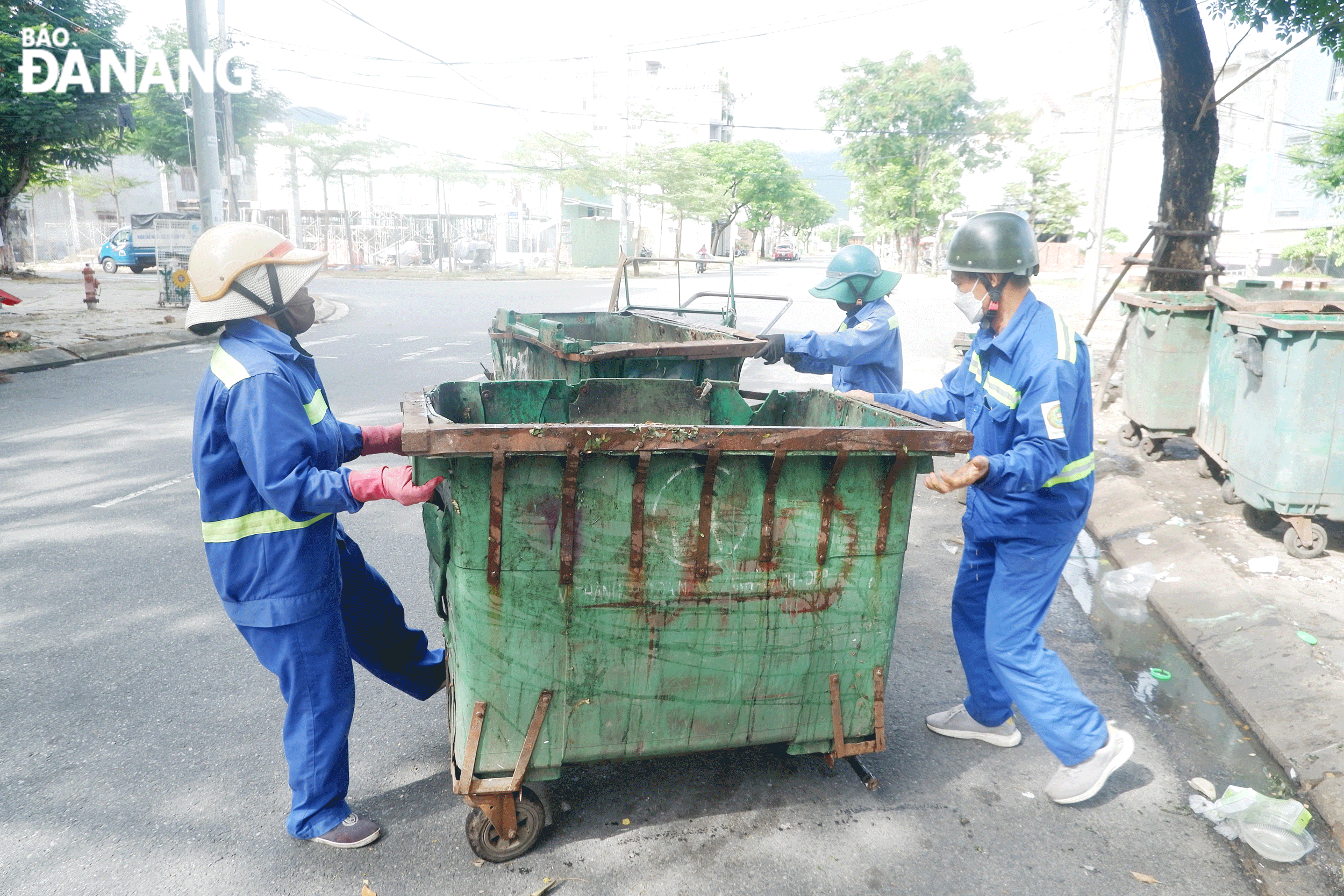 Chị Văn Thị Hạnh (bên trái) cùng các công nhân đang thu gom các thùng rác hỏng để chở về xí nghiệp. Ảnh: M.Q