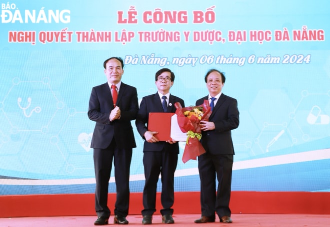 PGS.TS. Nguyễn Ngọc Vũ, Giám đốc Đại học Đà Nẵng (bên phải) và TS.Phan Minh Đức, Chủ tịch Hội đồng Đại học Đà Nẵng trao Nghị quyết thành lập Trường Y Dược và tặng hoa chúc mừng. Ảnh: NGỌC HÀ