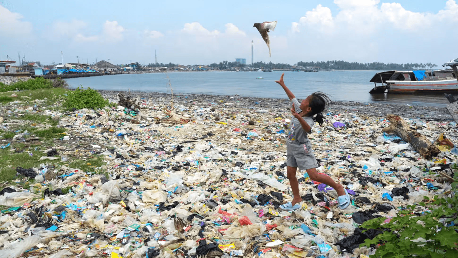 Một bé gái đang chơi đùa trên đống rác thải nhựa bẩn trôi dạt vào bãi biển Labuan ở phía tây Java, Indonesia. Ảnh: Nikkei Asia