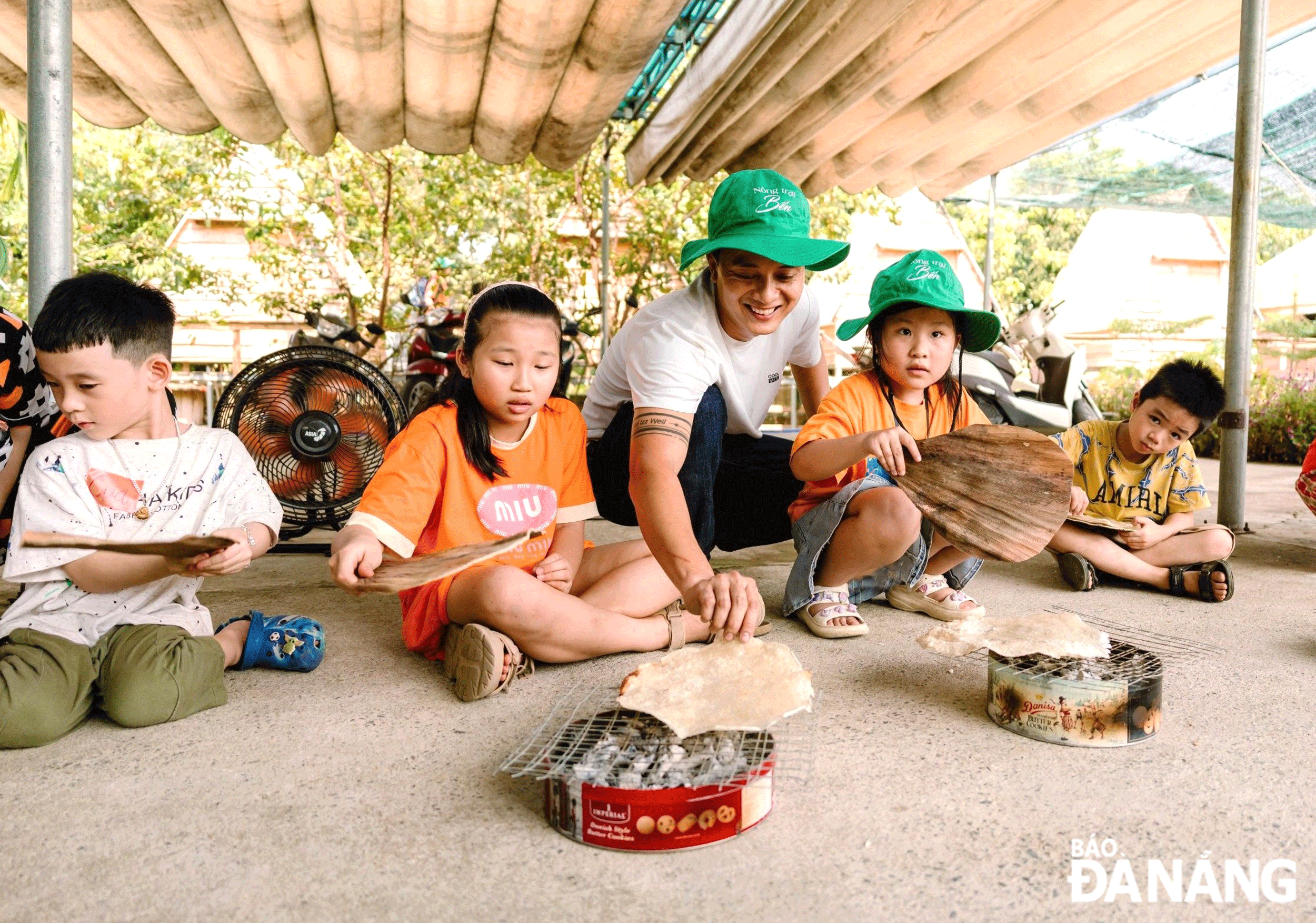 Anh Ngô Văn Quốc Huy là một trong những thanh niên thành công với mô hình kinh doanh dịch vụ kết hợp với du lịch trải nghiệm tại huyện Hòa Vang.  TRONG ẢNH: Hướng dẫn các em nhỏ cách nướng bánh tráng.Ảnh: Q.H