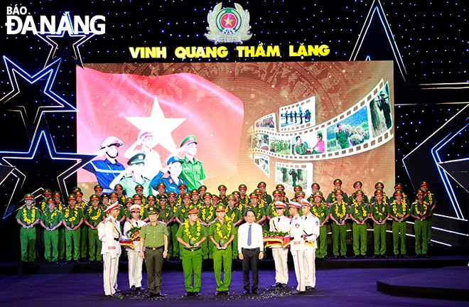 Phó Bí thư Thường trực Thành ủy Nguyễn Đình Vĩnh đeo vòng hoa và tặng kỷ niệm chương cho các chiến sĩ công an xã tiêu biểu. Ảnh: X.D