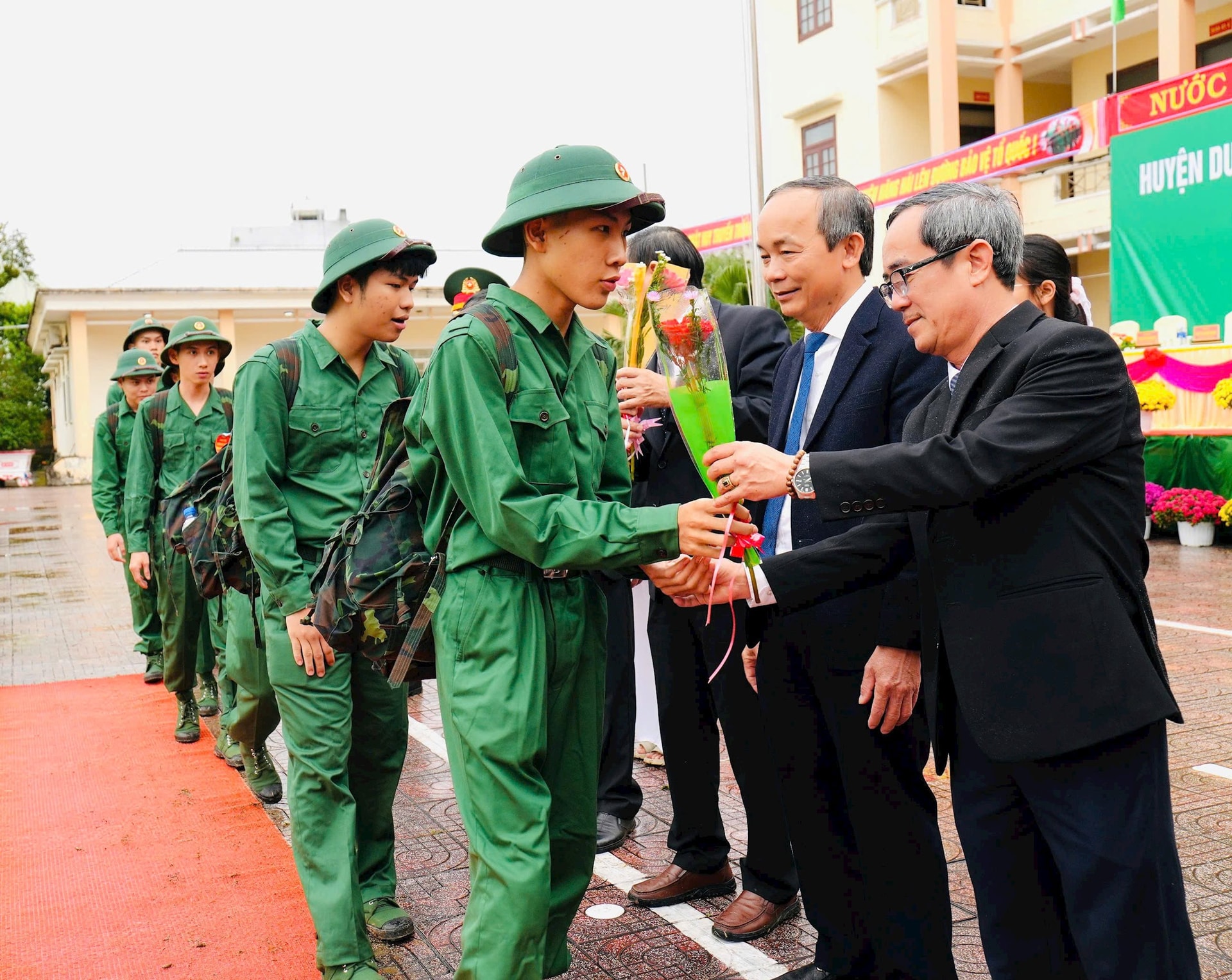 Lãnh đạo huyện Duy Xuyên tặng hoa động viên tân binh. Ảnh PHI THÀNH