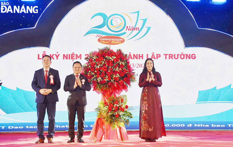 Phó Chủ tịch UBND thành phố Nguyễn Thị Anh Thi (ngoài cùng, bên phải) tặng hoa chúc mừng nhà trường. Ảnh: THU HÀ