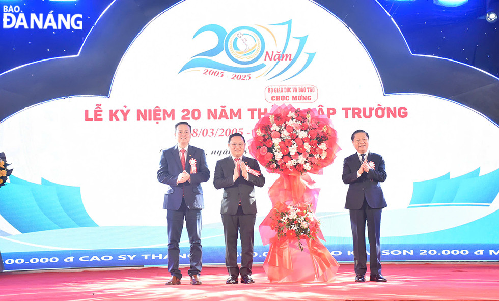 Thứ trưởng Bộ Giáo dục và Đào tạo Lê Tấn Dũng  (ngoài cùng, bên phải) tặng hoa, chúc mừng nhà trường nhân kỷ niệm 20 năm. Ảnh: THU HÀ