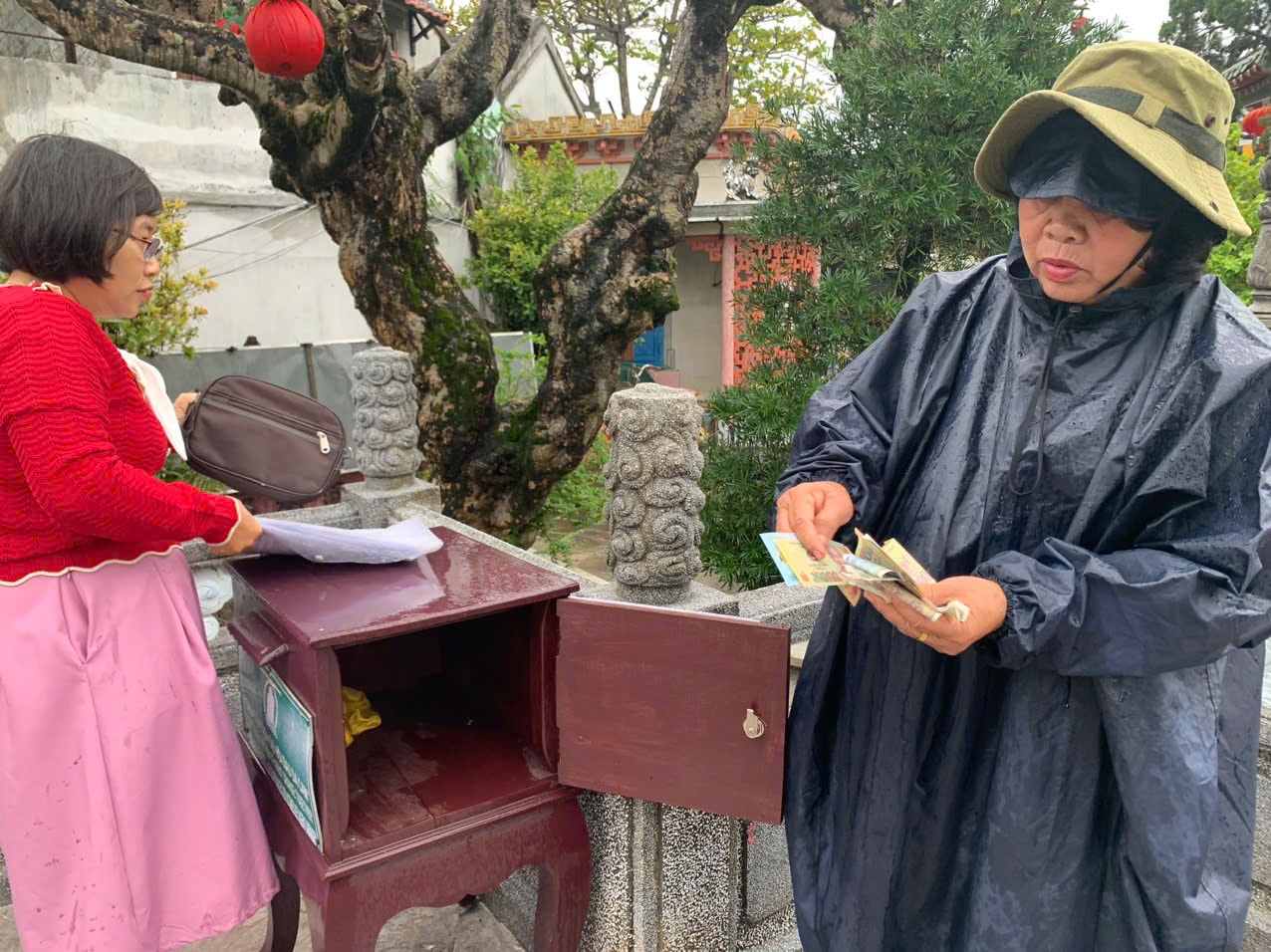 Bào Võ Thị Hóa - Chủ tịch Hội Nạn nhân chất độc da cam/dioxin TP.Hội An (bên phải) khui thùng thiện nguyện giúp đỡ nạn nhân chất độc da cam đặt tại Hội quán Phúc Kiến (Hội An). Ảnh: Hà Quang