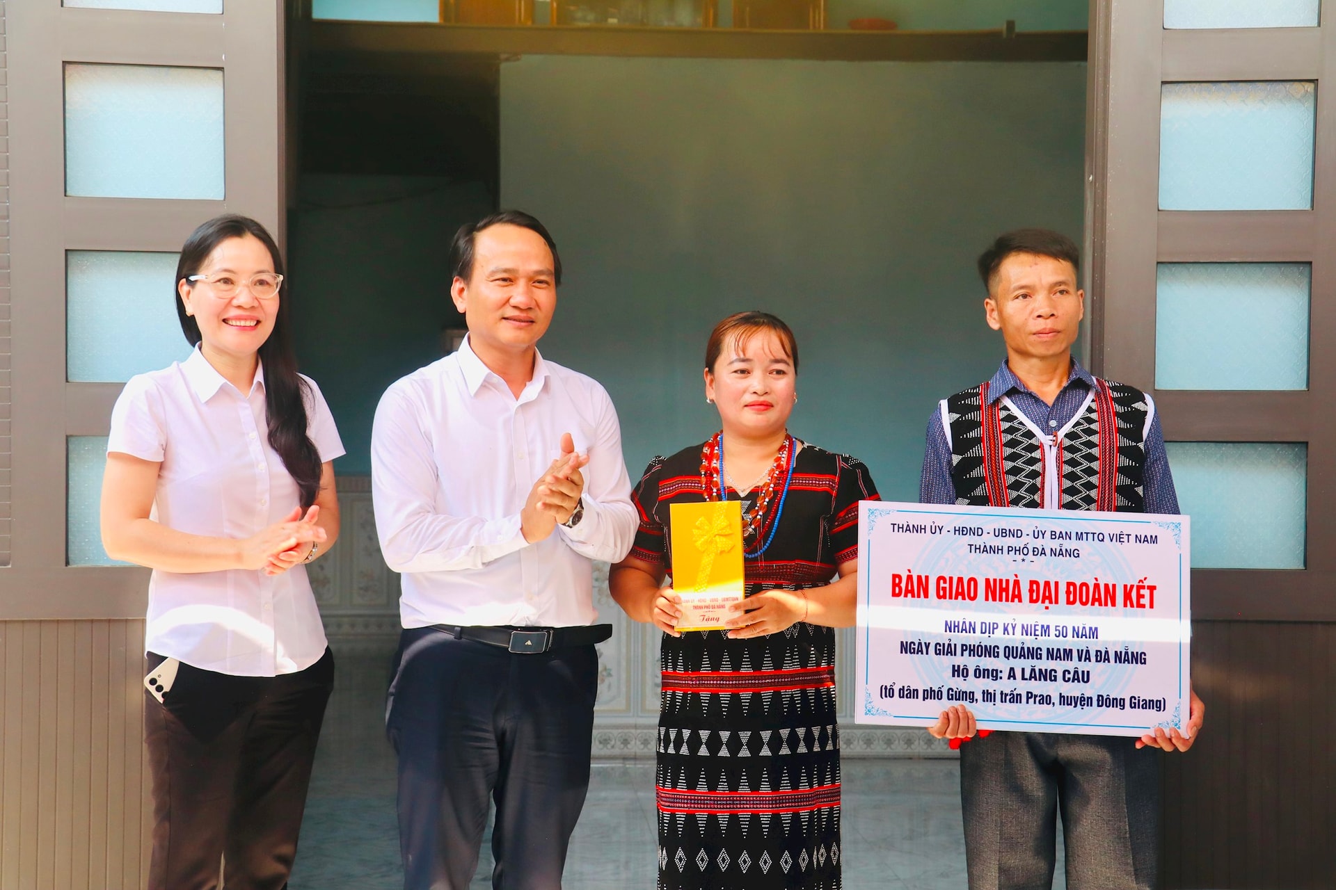 Phó Bí thư Thường trực Thành ủy Đà Nẵng trao bảng biểu trưng nhà đại đoàn kết và quà cho hộ ông Alăng Câu. Ảnh: QUỐC TUẤN