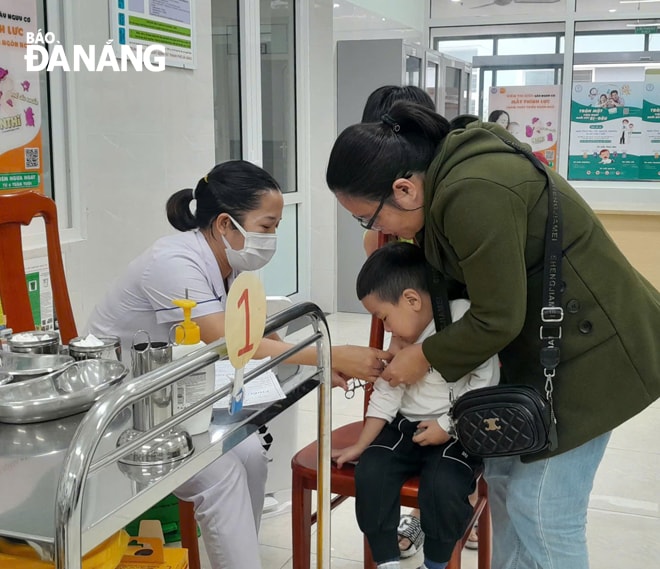 Nhân viên Trung tâm Kiểm soát bệnh tật thành phố tiêm vắc-xin phòng, chống sởi cho trẻ em. Ảnh: LÊ HÙNG