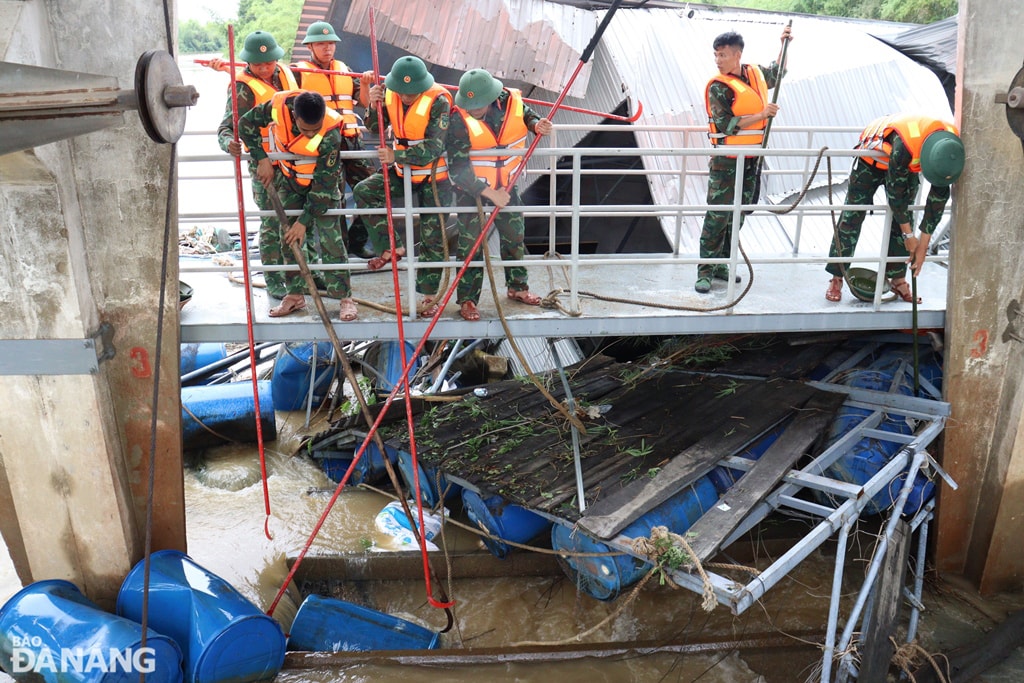 Bộ đội tháo dỡ lồng bè bị mắc kẹt ở các khoang thoát lũ của đập dâng An Trạch. Ảnh: HOÀNG HIỆP