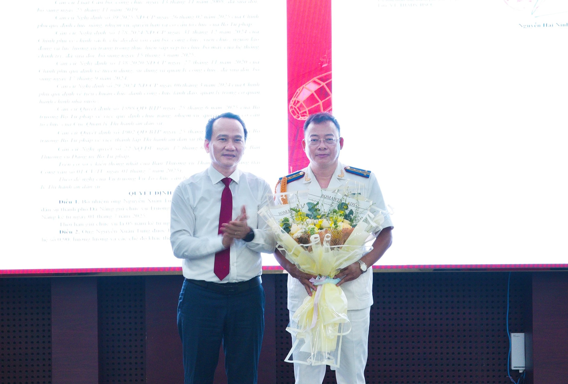 Phó Bí thư Thường trực Thành ủy Nguyễn Đình Vĩnh (bân trái) tặng hoa chúc mừng Trưởng Thi hành án dân sự thành phố Đà Nẵng Nguyễn Xuân Tùng. Ảnh: T.PHƯƠNG