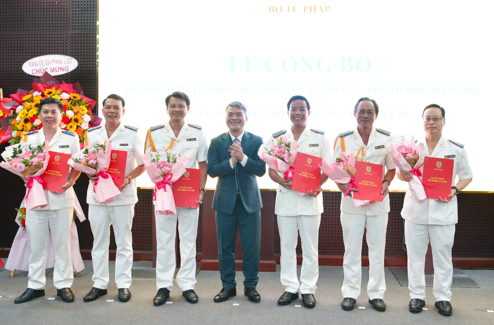 Thứ trưởng Bộ Tư pháp Nguyễn Thanh Tú (ở giữa) trao quyết định và tặng hoa chúc mừng các Phó trưởng Thi hành án dân sự thành phố Đà Nẵng. Ảnh: T.PHƯƠNG