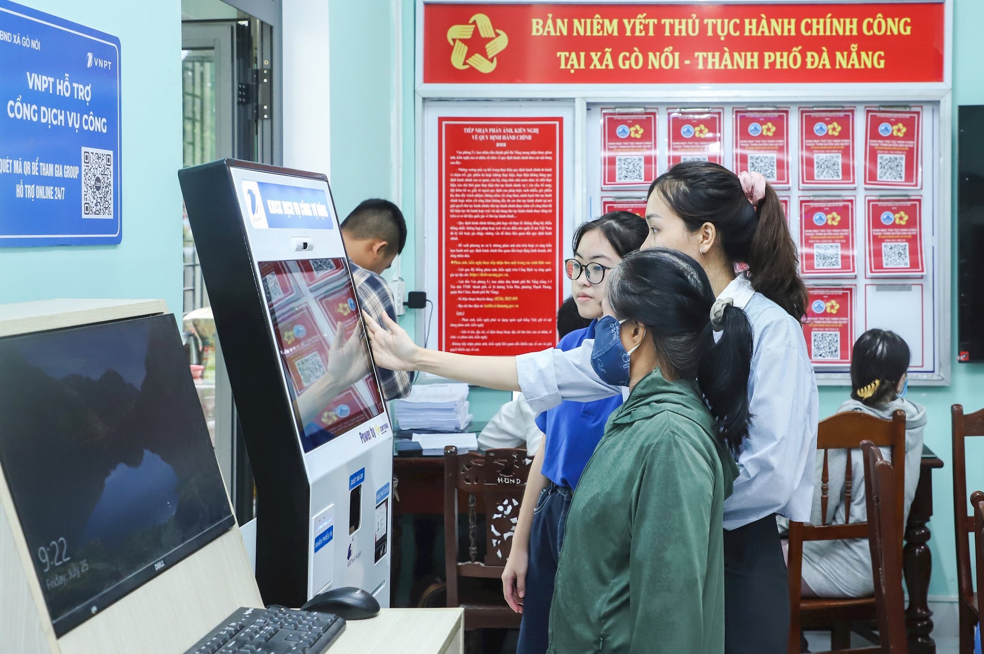 Cán bộ, công chức và thanh niên xã Gò Nổi hướng dẫn người dân thực hiện quy trình bấm số để làm các thủ tục hành chính. Ảnh: NGỌC PH