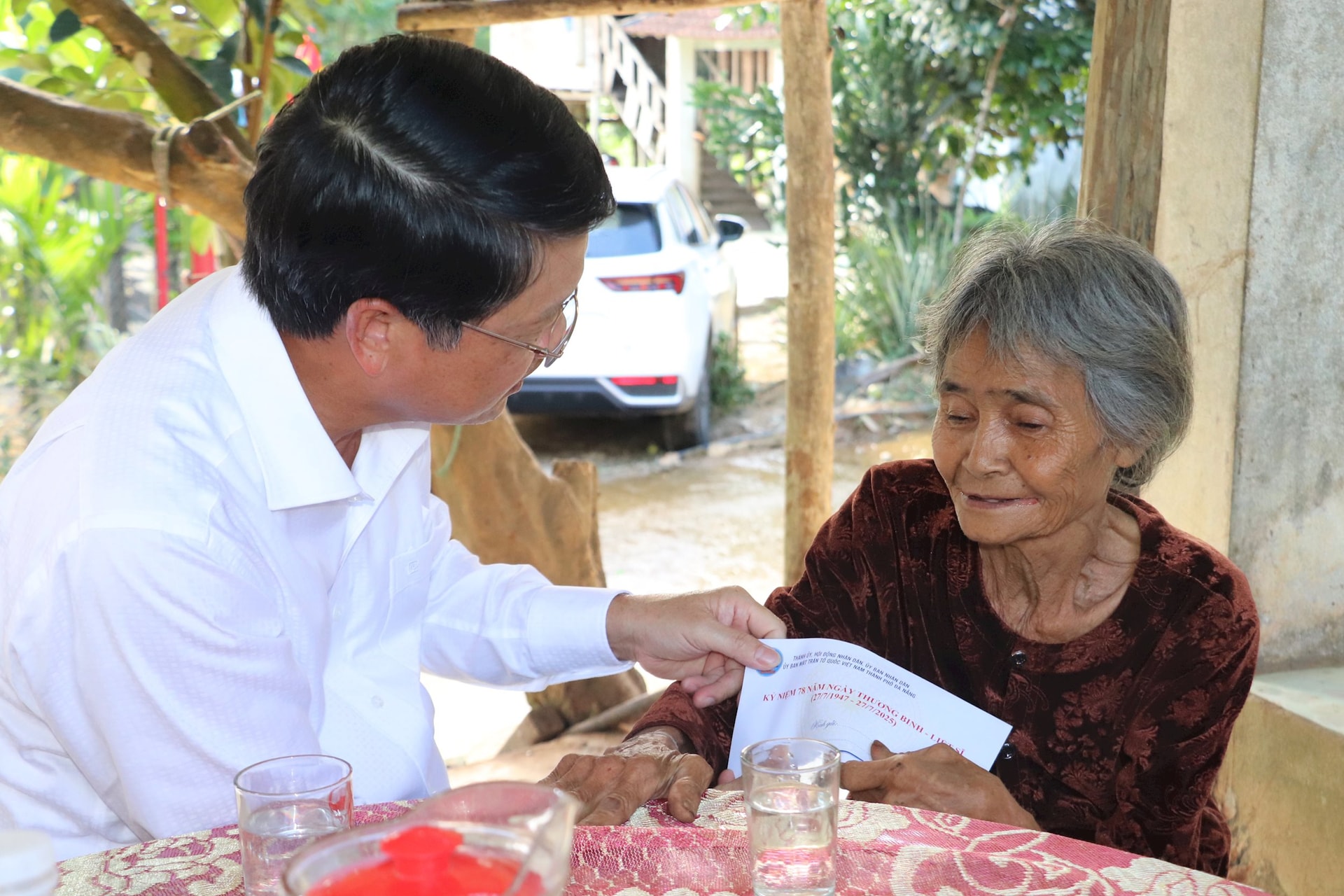 BPhó Bí thư Thành ủy Ngô Xuân Thắng tặng quà cho bệnh binh Đinh Thị Teo (78 tuổi, trú thôn 1, xã Trà Tân). Ảnh: ĐẮC MẠNH