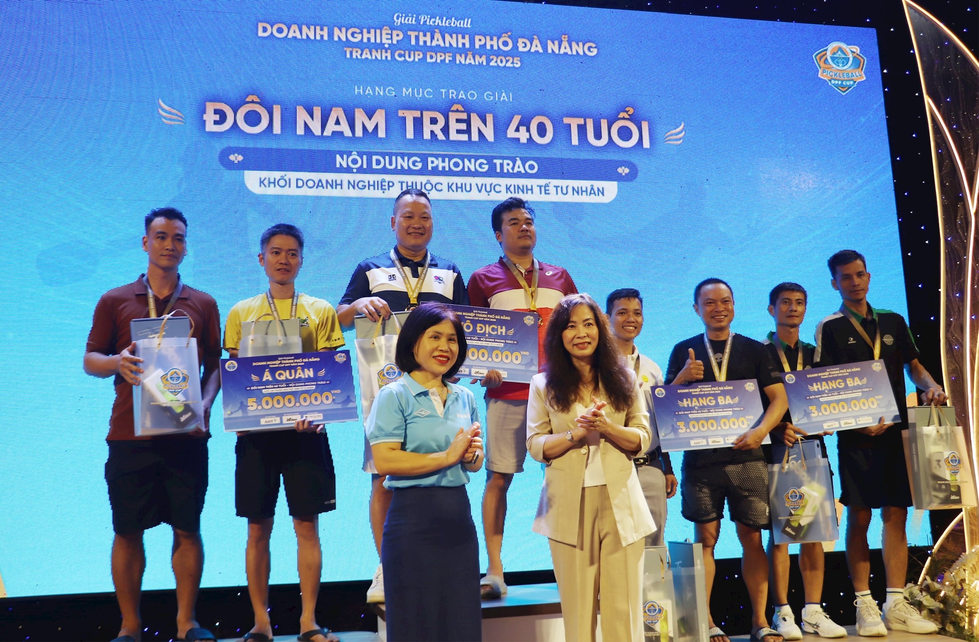 Giám đốc Sở Văn hóa – Thể thao và Du lịch thành phố Trương Thị Hồng Hạnh (áo trắng, bên phải) và Phó Trưởng Ban Tuyên giáo và Dân vận Thành ủy Nguyễn Thị Kim Hoa (áo xanh, trái) trao giải cho nội dung đôi nam trên 40 tuổi, Khối Doanh nghiệp tư nhân. Ảnh: ĐẮC MẠNH