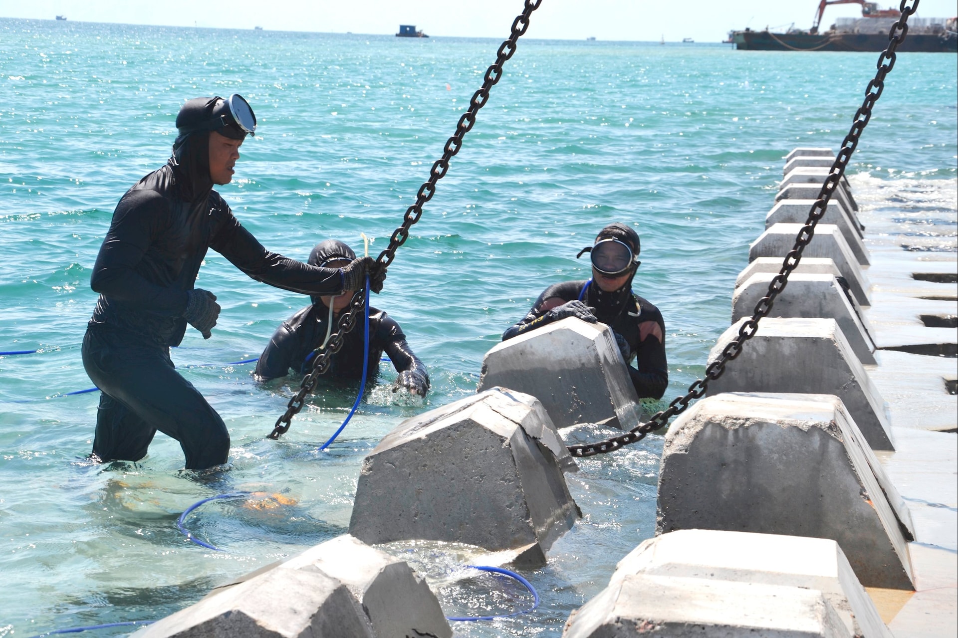 Công nhân lặn thi công đê giảm sóng xuyên trưa. Ảnh: CÔNG TÚ