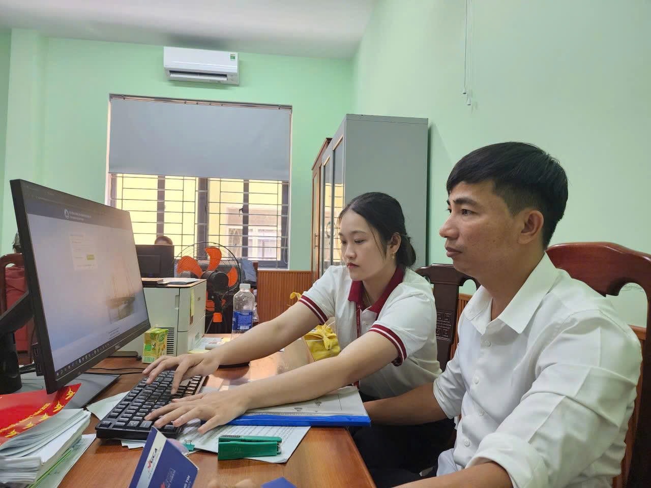 Sinh viên Trần Thị Mai Trinh (bên trái), Khoa Công nghệ thông tin (Đại học Duy Tân) hỗ trợ cán bộ phường Điện Bàn Bắc làm chữ ký số. Ảnh: N.QUỐC