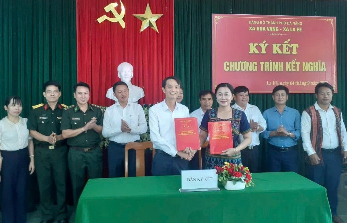 Phó Bí thư Thường trực Đảng ủy xã Hòa Vang Lê Văn Hùng Vương (hàng đầu, bên trái) và Phó Bí thư Thường trực Đảng ủy xã La Êê A Rất Thị Hoa trao văn bản ký kết hợp tác giữa hai địa phương. Ảnh: VĂN THỦY