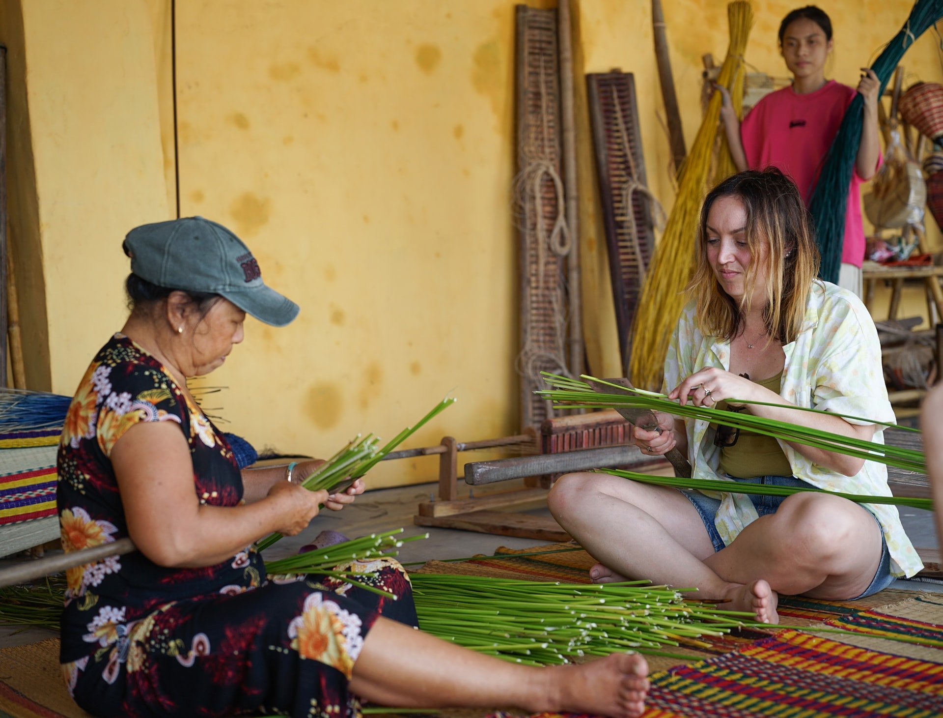 Ms. Charlotte White, a tourist from the Netherlands, tries splitting sedge for mat weaving. Photo: XUAN SON