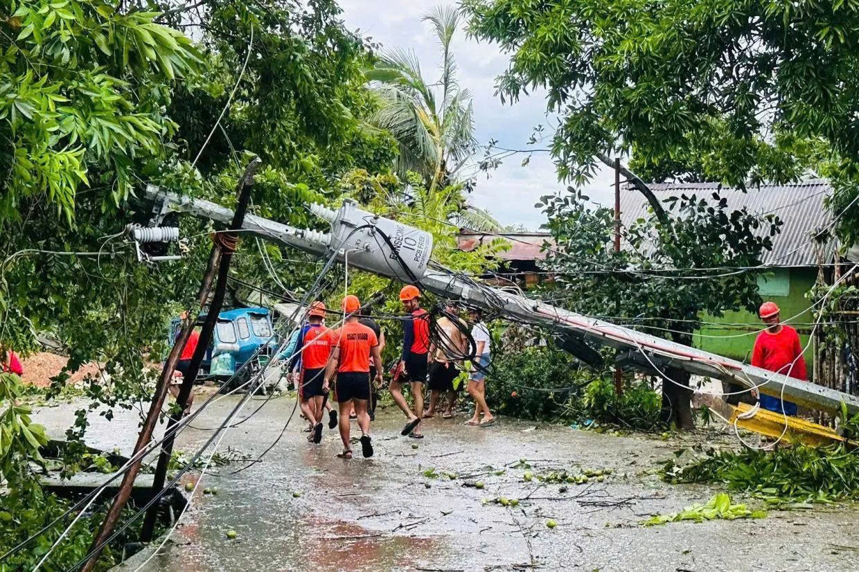 Trong bức ảnh do Lực lượng bảo vệ bờ biển Philippines cung cấp, các thành viên của Lực lượng bảo vệ bờ biển Philippines đi bộ bên cạnh một cột điện bị đổ do Bão nhiệt đới Bualoi ở thành phố Romblon, tỉnh Romblon, Philippines vào thứ sáu ngày 26 tháng 9 năm 2025. - Lực lượng bảo vệ bờ biển Philippines qua AP