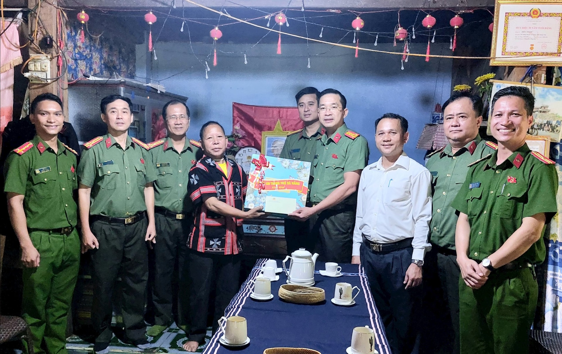 Đại tá Nguyễn Đại Đồng, Phó Giám đốc Công an thành phố và lãnh đạo Công an xã Sông Kôn thăm, tằng quà cho già làng Bhriu Thiện. Ảnh LÊ HÙNG