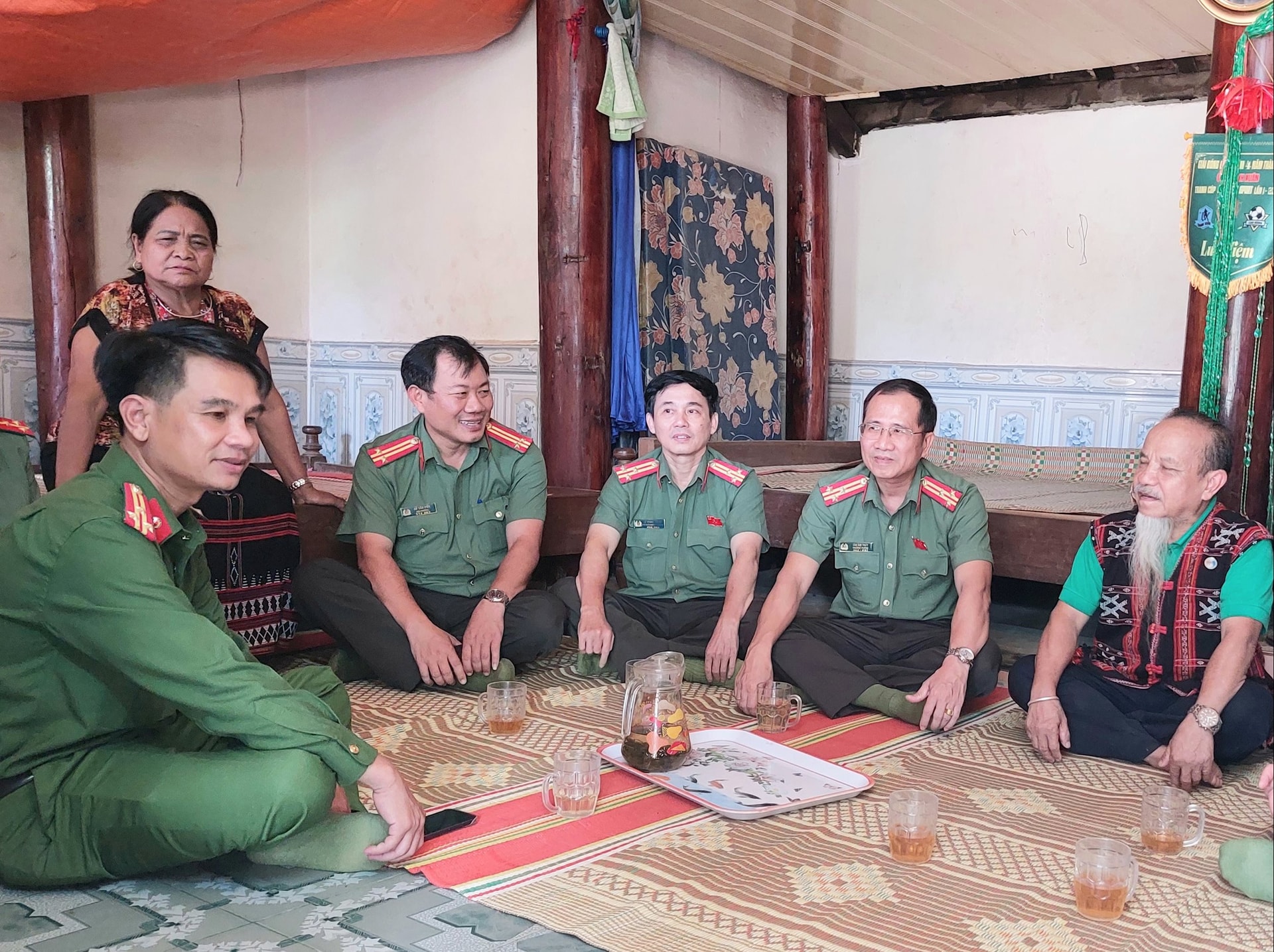 Lực lượng công an trò chuyện cùng già làng Clâu Nhím trong công tác vận động nhân dân giữ gìn an ninh trật tự. Ảnh LÊ HÙNG