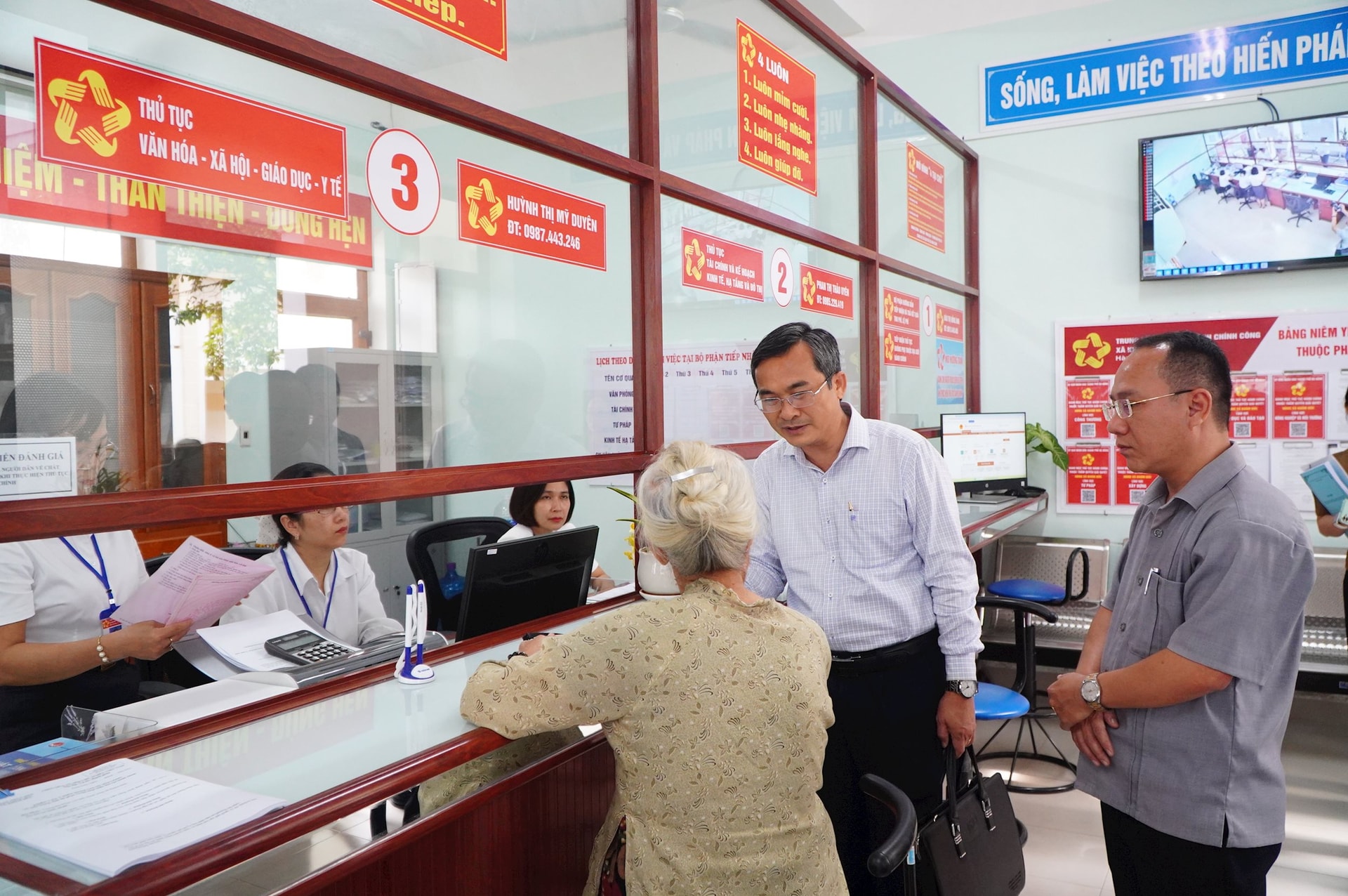 Phó Chủ tịch Ủy ban MTTQ Việt Nam thành phố Nguyễn Phi Hùng (đứng giữa) trao đổi với bà Trần Thị Hòa tại Trung tâm Phục vụ hành chính công xã Khâm Đức. Ảnh VINH ANH
