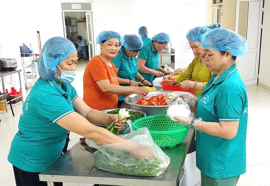 Membros da Associação de Mulheres de Khue Trung 24 preparam refeições juntas para distribuir aos pacientes. Foto: LAM PHUONG