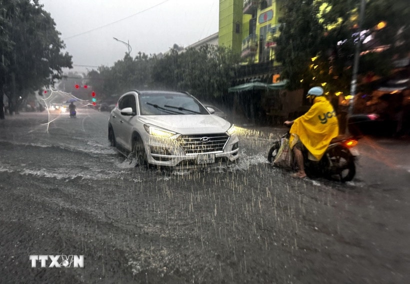 Người và phương tiện gặp nhiều khó khăn khi lưu thông qua các tuyến đường tại thành phố Đồng Hới (Quảng Trị) bị ngập sâu. (Ảnh: TTXVN phát)
