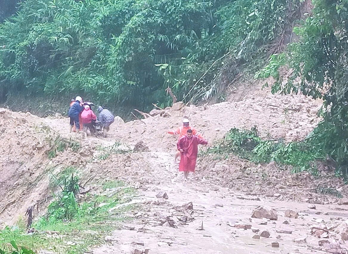 يدفع الناس دراجات نارية عبر منطقة انهيار أرضي على الطريق السريع 40B عبر منطقة نوك فين، بلدية ترا تان في صباح يوم 27 أكتوبر. الصورة: فان بينه