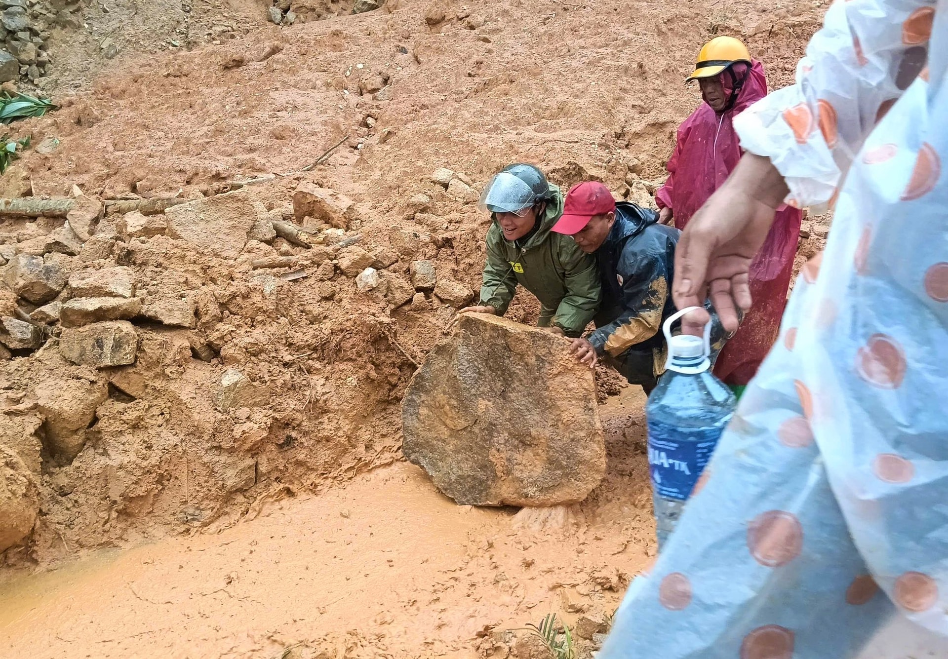 Người dân hợp sức đẩy tảng đá lớn, nhằm khơi thông tuyến đường. Ảnh: THÀNH NGUYỄN