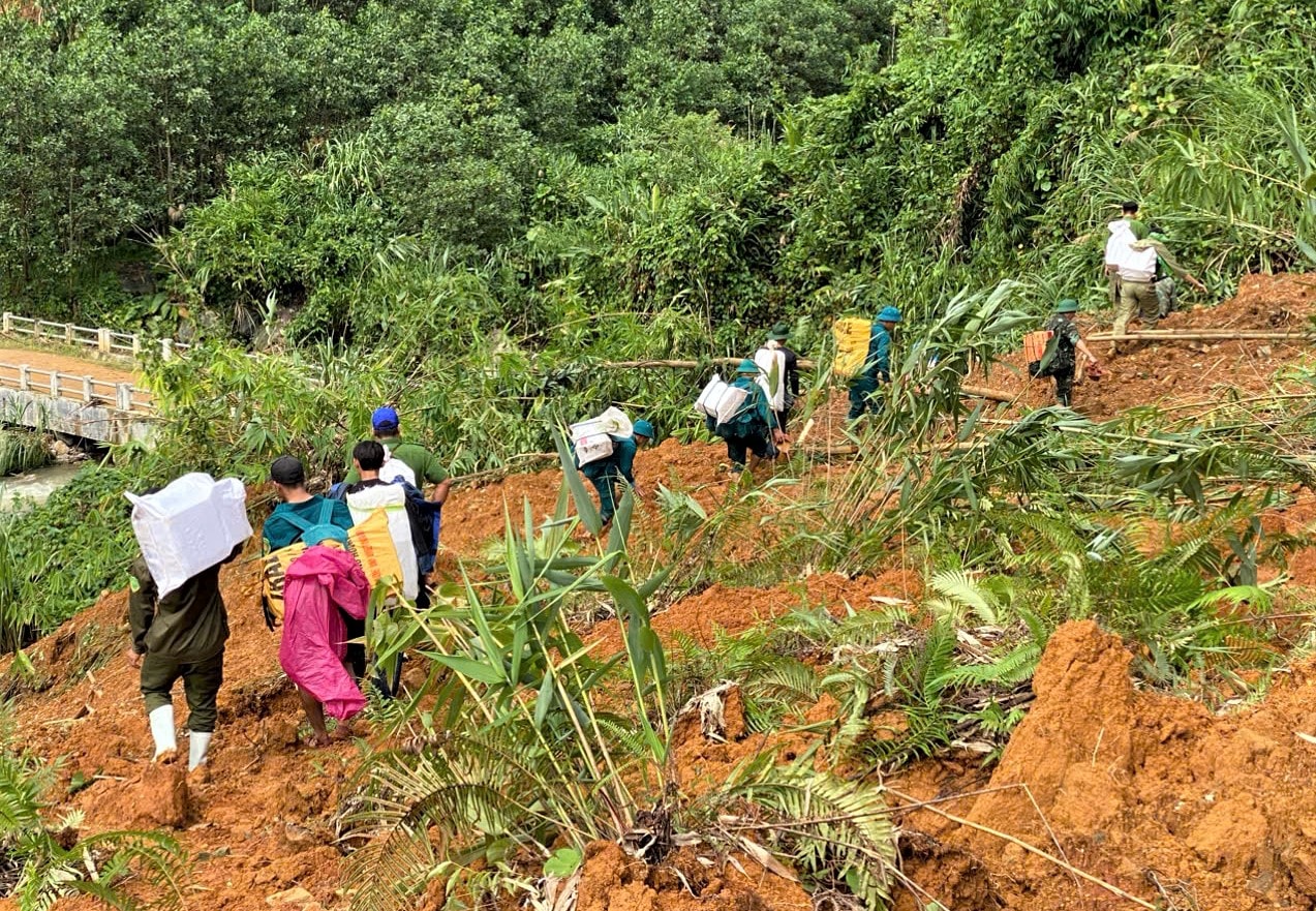 Petugas komune Tra Leng melintasi lokasi longsor untuk mengantarkan makanan kepada warga yang terisolasi. Foto: VAN HO