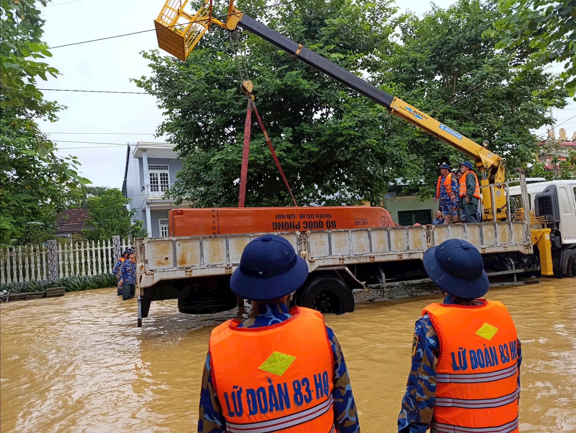 Lữ đoàn Công binh 83 phối hợp lực lượng chức năng sử dụng xe cẩu, xuồng máy đưa lương thực đến với người dân. Ảnh: LÊ HÙNG