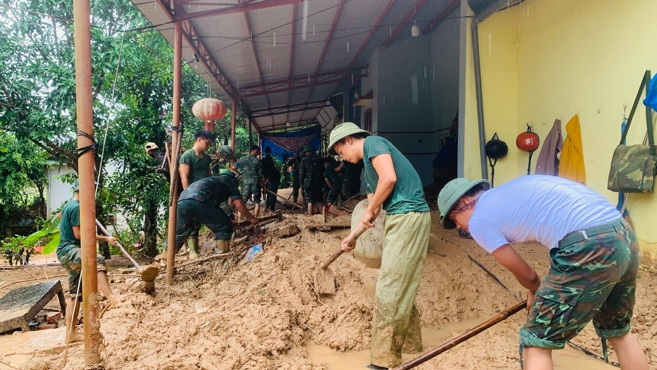 Officers and soldiers of the 574th Armored Brigade help Que Phuoc residents clean up mud after the flood. Photo: MINH THONG