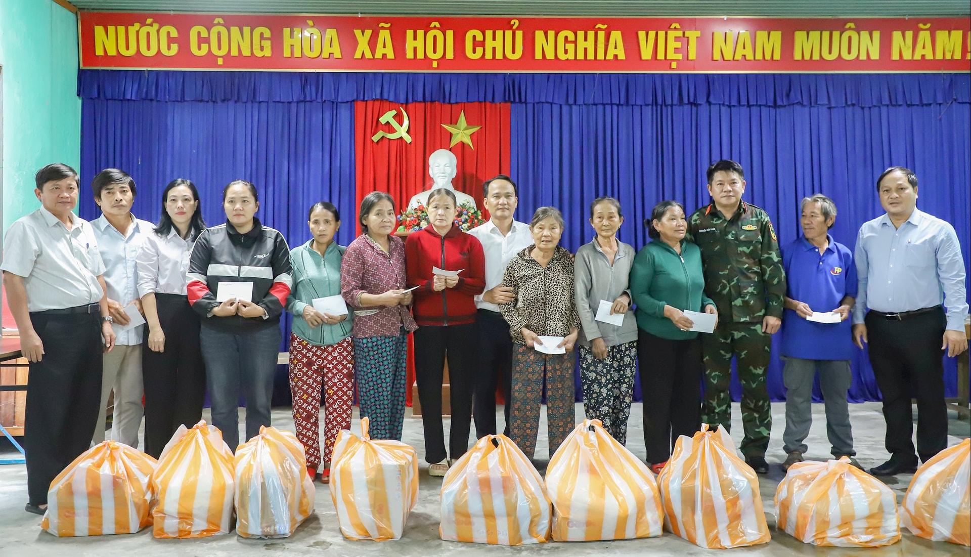 Phó Bí thư Thường trực Thành ủy Nguyễn Đình Vĩnh (thứ 8, trái sang) trao quà hỗ trợ người dân tại xã Quế Sơn Trung. Ảnh: NGỌC PHU