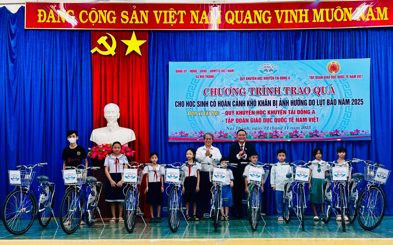 Dr. Nguyen Duc Quoc - styrelseordförande för Nam Viet International Education Group, Ho Chi Minh City (svart väst) ger cyklar till missgynnade elever. Foto: XUAN HIEU