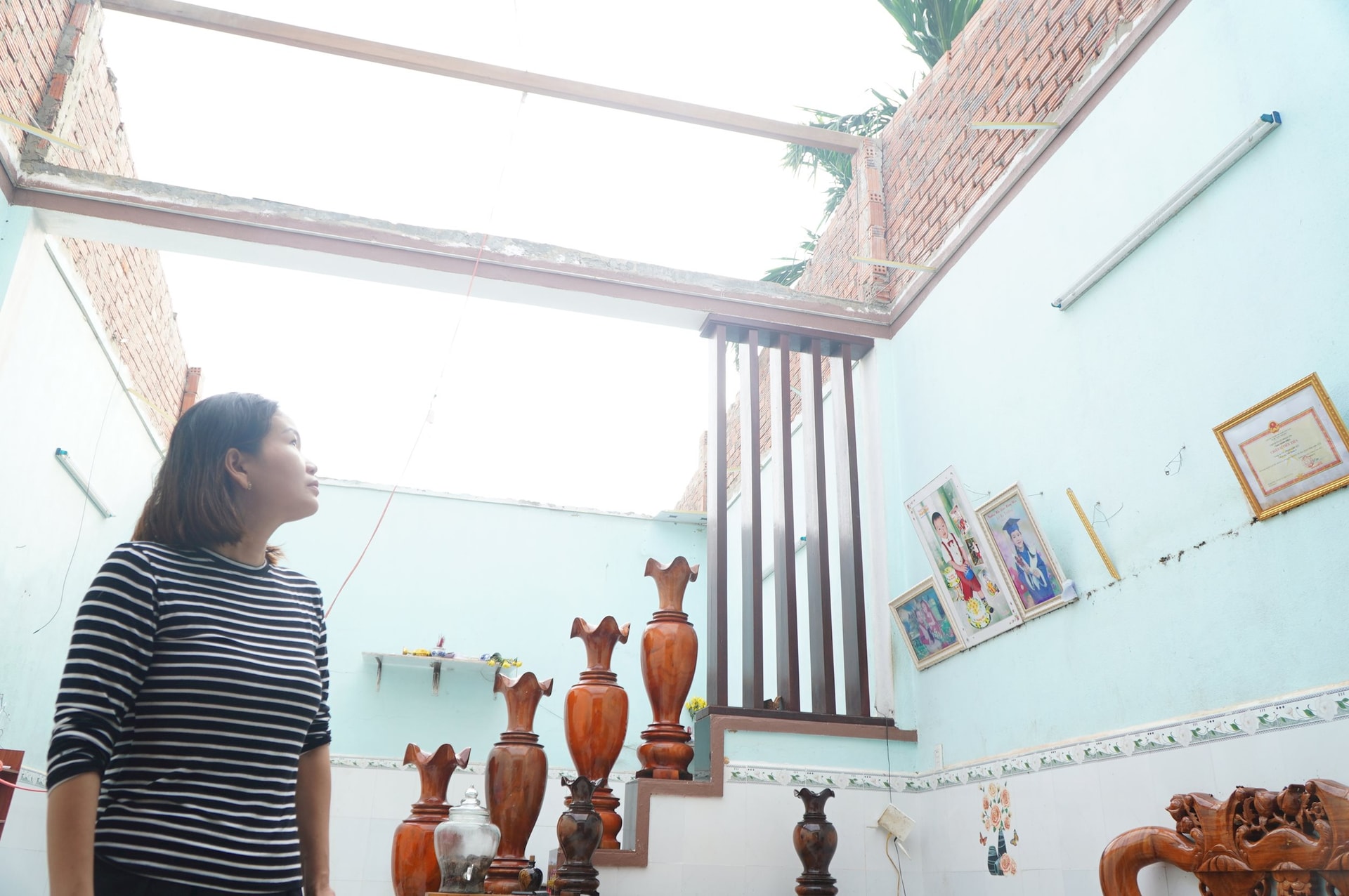 អ្នកស្រី Le Thi My Nga (ក្រុមសាមគ្គីលេខ៦ ក្រុមលំនៅដ្ឋាន Hoa Lang) បានសម្លឹងមើលផ្ទះរបស់នាងដោយឥតលាក់លៀម ដែលដំបូលផ្ទះត្រូវបានខ្យល់ព្យុះកំបុតត្បូង។ រូបថត៖ TAM DAN