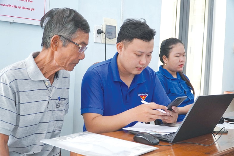 Lực lượng đoàn viên thanh niên phường Quảng Phú hỗ trợ người dân làm thủ tục hành chính tại Trung tâm Phục vụ hành chính công phường. Ảnh: N.ĐOAN
