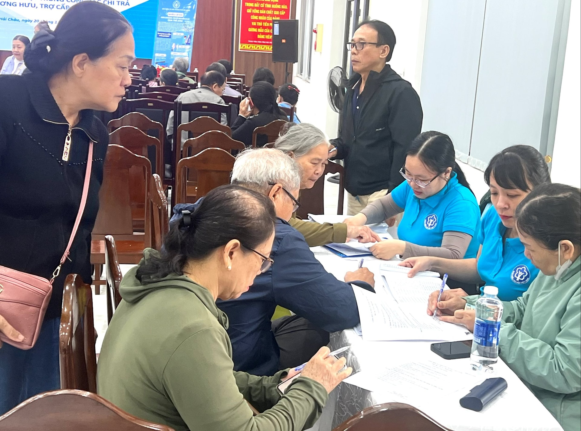 Người dân được đại diện BHXH và ngân hàng tư vấn, hỗ trợ, giải thích về các lợi ích khi sử dụng thanh toán không dùng tiền mặt. Ảnh: DUYÊ
