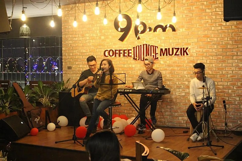 Không gian một quán cafe nhạc sống tại Hà Nội với sân khấu và ánh đèn ấm cúng.