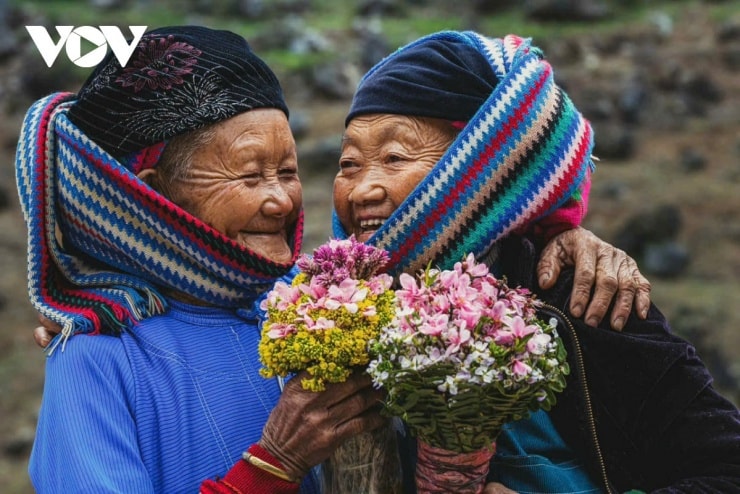 Các cụ bà người Lô Lô trong trang phục truyền thống cầu kỳ ngồi bên hiên nhà.